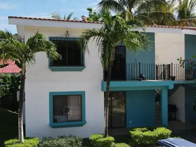 a white building with palm trees in front of it at Minimalist Condo with a Beautiful New Design, Bound Patio, and Shared Community Pool in Coco