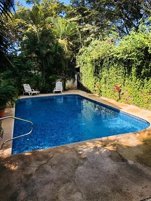 a swimming pool in a yard with two chairs at La buena vida ocean Tamarindo in Libertad