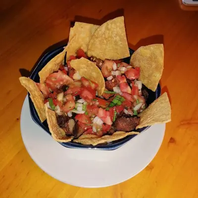 a plate of nachos with salsa and chips on a table at la casona rio in Alajuela City