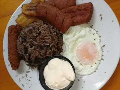 a plate of breakfast food with eggs and meat and french fries at la casona rio in Alajuela City