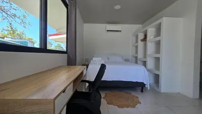a bedroom with a bed and a desk and a window at Mango Coliving Rooms for Digital Nomads in Uvita
