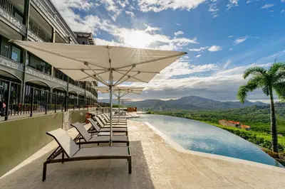 a row of chairs with umbrellas next to a pool at 360 Splendor 208F- Ocean View Condo, Breakfast in Playa Flamingo