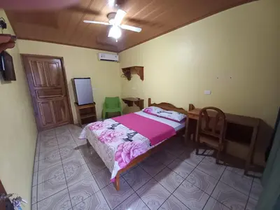 a bedroom with a bed and a desk and a television at Cabinas Ruma in Muelle