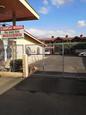 a fence in front of a building with a sign at Cabinas Ruma in Muelle