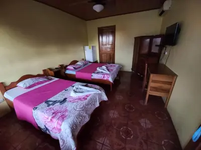 a room with two beds and a television in it at Cabinas Ruma in Muelle