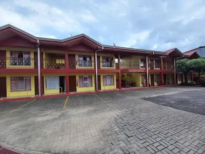a red and yellow building with a parking lot at Cabinas Ruma in Muelle