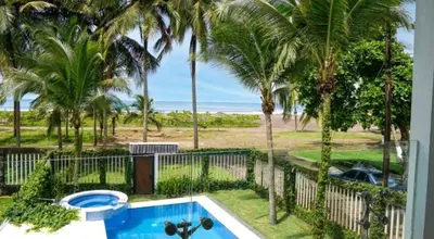 a view of a swimming pool with palm trees and the beach at Millys House 6p max Jacó CR in Jacó
