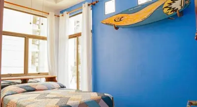 a bedroom with a bed and a surfboard on the wall at Millys House 6p max Jacó CR in Jacó