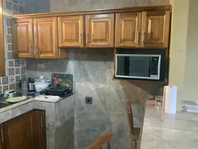 a kitchen with wooden cabinets and a microwave at Pinky s Place Alajuela City Airport Costa Rica in Alajuela City