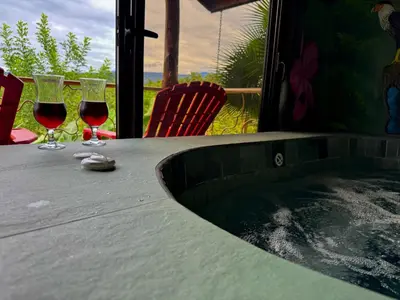two glasses of wine sitting on a table next to a tub at Villa Lomas Sarapiquí in Colonia Carvajal