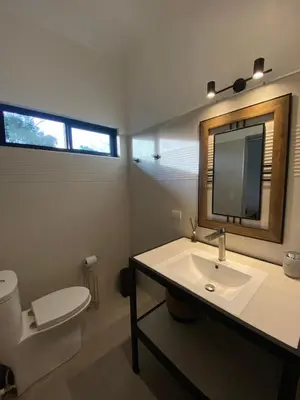 a bathroom with a sink and a toilet and a mirror at Finca Quietud in Tarcoles