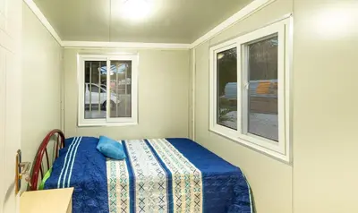 a small bedroom with a bed and two windows at Beautiful tiny house with AC WIFI in Santa Cruz