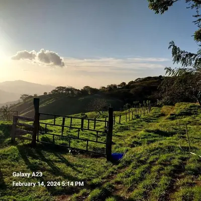 a fence in a field with a view of a mountain at Sunset Farms and Waterfalls! in Tilarán