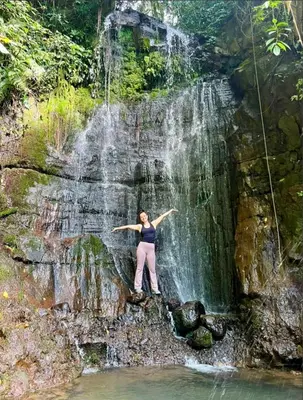 a woman standing in front of a waterfall at Sunset Farms and Waterfalls! in Tilarán