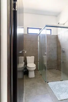 a bathroom with a toilet and a glass shower stall at Quinta Bella in Bagaces