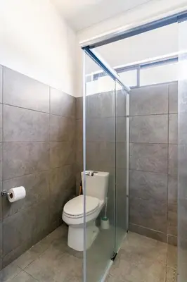a bathroom with a toilet and a glass shower stall at Quinta Bella in Bagaces