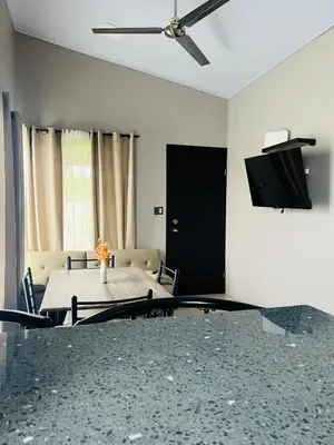 a living room with a table and a ceiling fan at Epic Arenal View House in Fortuna