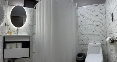 a white bathroom with a shower curtain and a toilet at Epic Arenal View House in Fortuna