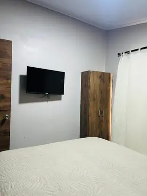 a bedroom with a bed and a flat screen tv on a wall at Epic Arenal View House in Fortuna