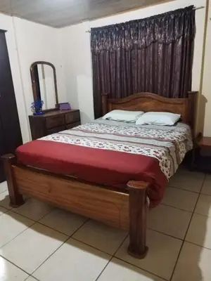 a bedroom with a wooden bed with a red blanket at La posada Escondida in Morazán