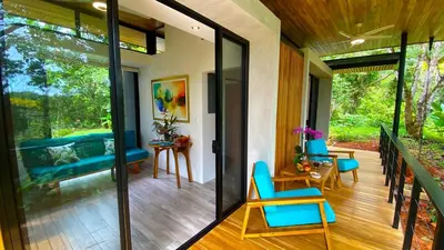 a living room with glass doors and blue chairs at Casita Jungle Nest, 5 minutes drive to Playa Linda, 15 to Dominical, Wifi Starlink in Matapalo