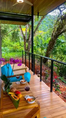a wooden deck with a table with food and wine glasses at Casita Jungle Nest, 5 minutes drive to Playa Linda, 15 to Dominical, Wifi Starlink in Matapalo