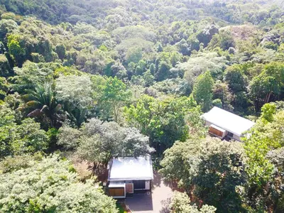 an aerial view of a forest of trees with two buildings at Casita Jungle Nest, 5 minutes drive to Playa Linda, 15 to Dominical, Wifi Starlink in Matapalo