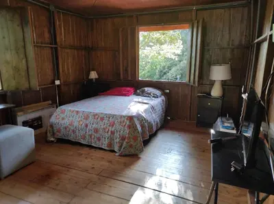 a bedroom with a bed and a tv in it at CASA CON PISCINA Montañas de San Ramón in San Ramón