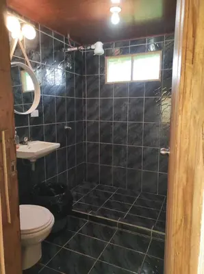 a black tiled bathroom with a toilet and a sink at CASA CON PISCINA Montañas de San Ramón in San Ramón