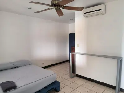 a bedroom with a bed and a ceiling fan at La Hacienda Rooms & Food in Jacó
