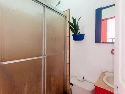 a bathroom with a shower with a toilet and a sink at La Hacienda Rooms & Food in Jacó