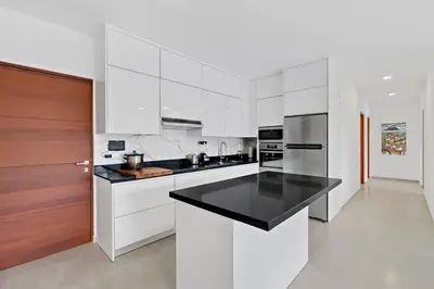 a kitchen with white cabinets and a black counter top at Casa Corales Dreams 2 in Playa Flamingo