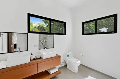 a bathroom with two sinks and a toilet and two windows at Casa Corales Dreams 2 in Playa Flamingo