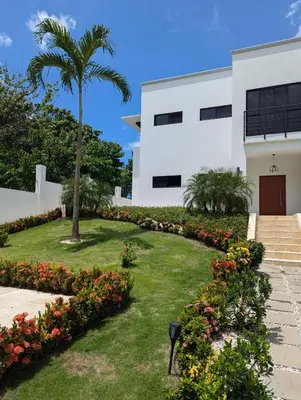 a white building with a palm tree and flowers at Casa Corales Dreams 2 in Playa Flamingo