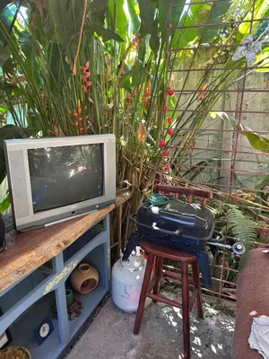 a television sitting on a table next to a chair with a grill at Yellow House in Huacalillo