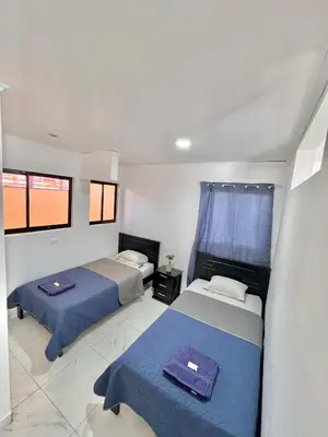 a bedroom with two beds and two windows at Global House Apartamento 2 in Alajuela City