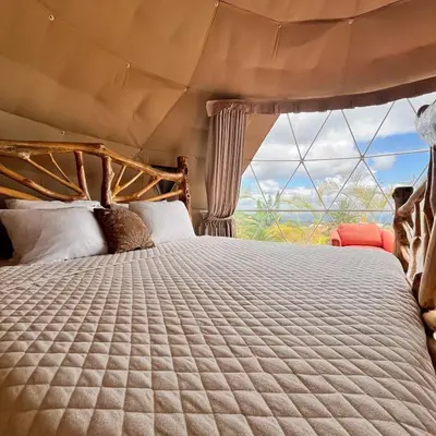a bedroom with a bed with a large window at Love Glamping Dome in El Hogar