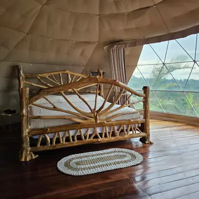 a wooden bed in a room with a large window at Love Glamping Dome in El Hogar