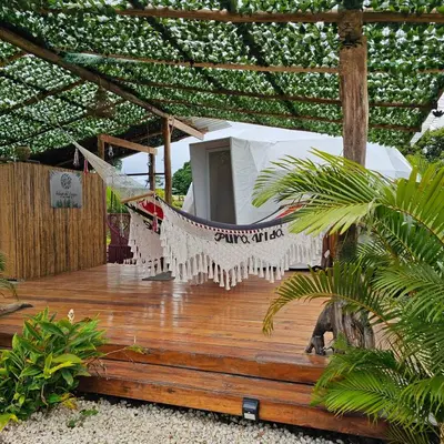 a hammock on a wooden deck with a tent at Love Glamping Dome in El Hogar