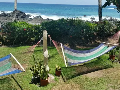 two hammocks on the grass next to the beach at Hotel Cabinas Mar Y Cielo in Montezuma
