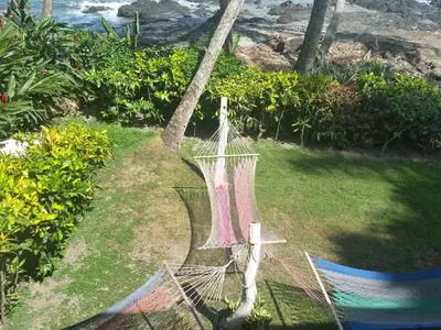 a hammock on the grass next to the ocean at Hotel Cabinas Mar Y Cielo in Montezuma