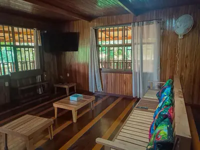 a living room with benches and a tv and windows at Casa corazón verde in Jiménez