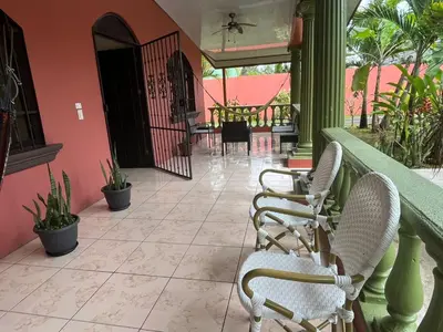 a porch with two chairs and a table on a patio at Villa tico House in Cariari