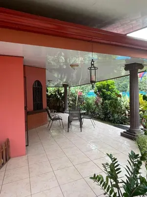 a patio with tables and chairs in a house at Villa tico House in Cariari