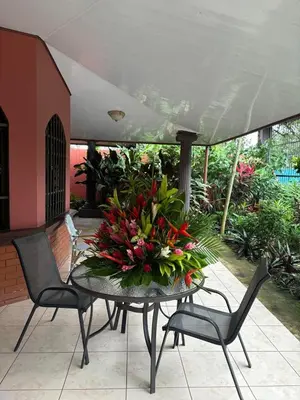 a table with a bouquet of flowers on a patio at Villa tico House in Cariari