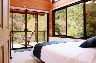 a bedroom with a bed and a balcony with windows at Casa Buena Vista San Gerardo de Dota in San Gerardo de Dota