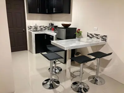 a kitchen with a white counter and stools at Hospedaje Ana Lu 3, Only 10 minutes from airport, in Alajuela City