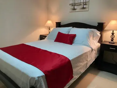 a bedroom with a large bed with a red blanket at Hospedaje Ana Lu 3, Only 10 minutes from airport, in Alajuela City