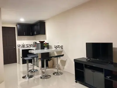 a kitchen with a table and stools and a television at Hospedaje Ana Lu 3, Only 10 minutes from airport, in Alajuela City