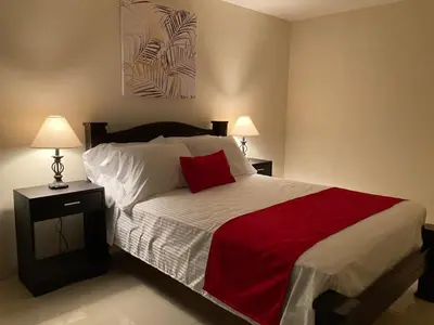 a bedroom with a bed with a red blanket and two lamps at Hospedaje Ana Lu 3, Only 10 minutes from airport, in Alajuela City